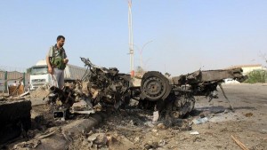 Man looks at the wreckage of a vehicle at the site of a suicide bombing in Yemen's southern port city of Aden