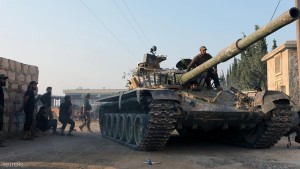 Rebel fighters ride a tank in an artillery academy of Aleppo