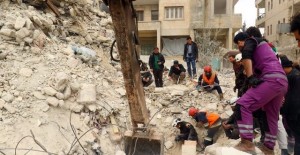 Civil Defence members and civilians remove rubble in a damaged site after an airstrike on Idlib city