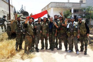 Soldiers loyal to the Syrian regime pose for a photograph as they gesture and hold the Syrian national flag in the village of Debaa near Qusair
