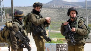 Israeli soldiers guard the road to the Israeli settlement Itamar where five family members were killed by a Palestinian late Friday night