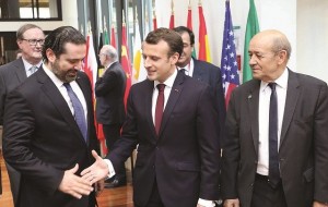 French President Emmanuel Macron, flanked by French Foreign Affairs Minister Jean-Yves Le Drian, shakes hands with Lebanese Prime Minister Saad Hariri during the Cedar Conference in Paris