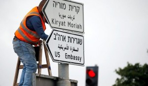 A worker hangs a road sign directing to the U.S. embassy, in the area of the U.S. consulate in Jerusalem