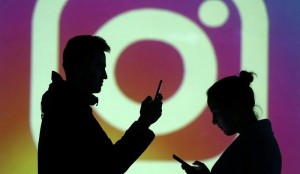 Silhouettes of mobile users are seen next to a screen projection of Instagram logo in this picture illustration