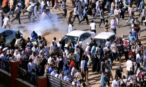 Sudanese demonstrators run from teargas lobbed to disperse them as they march along the street during anti-government protests in Khartoum
